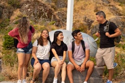 मिश्रित राष्ट्रीयताओं के अंग्रेजी छात्रों का समूह अंग्रेजी सीखने के कौशल के बारे में बाहर बात कर रहा है, हंस रहा है और अच्छा समय बिता रहा है।